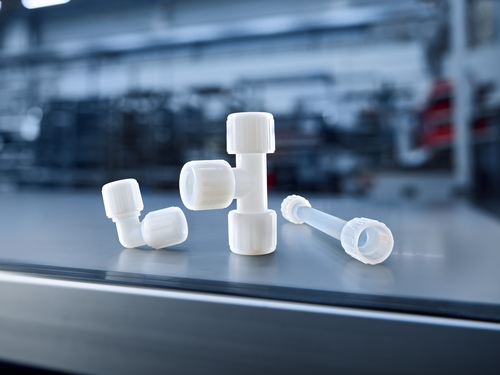 GEMÜ connection technology with plastic fittings and transparent tubing on a dark background.