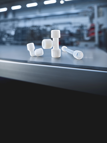 GEMÜ connection technology with plastic fittings and transparent tubing on a dark background.