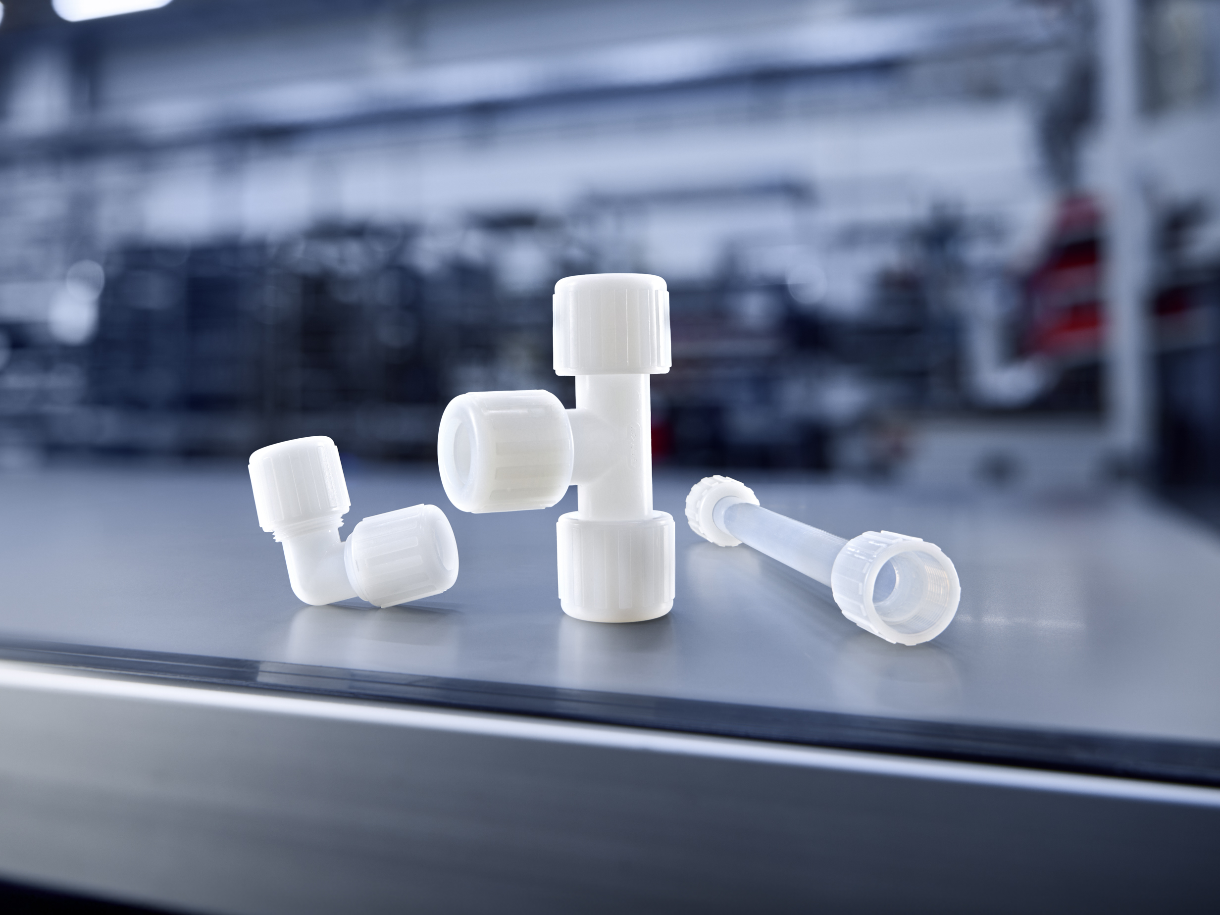 Technique de raccordement GEMÜ avec raccords en plastique et tuyau transparent sur fond sombre.